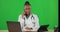 Woman, doctor and green screen with a laptop and phone call while talking and writing notes on research. Black female or