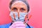 Woman doctor with insulin syringes in hand on a red background. A nurse girl in a medical mask is preparing for an injection,