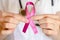 Woman doctor keeps a pink ribbon close up. Breast cancer examination concept