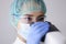 Woman doctor laboratory assistant in goggles and mask looks through microscope.