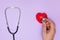 Woman doctor listens to work heart with stethoscope on purple background, flat lay.