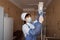 Woman doctor in medical gloves in a protective mask is standing and holding a drip in hands being in a hospital ward.
