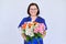 Woman doctor, nurse in blue with bouquet of flowers, on light background