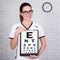 Woman doctor or nurse holding clipboard with eyevision test chart