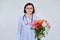 Woman doctor, nurse in white with bouquet of flowers, on light background