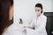 Woman at a doctor`s appointment in a white office. Confident general practice cosmetologist beautician wearing medical protective