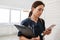 The woman doctor with stethoscope looking into the phone while holding a tablet with papers in hand