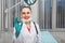 Woman doctor taking off his mask smiles at the camera and puts his hand okay against the background of a hospital ward