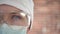 A woman doctor therapist in a white cap, mask and goggles. Face close-up. The doctor cry and prays. Tears in eyes