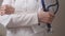 A woman doctor in a white coat holds a stethoscope in her hands, treatment and examination in a clinic, medical