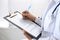 Woman doctor at work at hospital. Young female physician write prescription or filling up medical form while sitting in