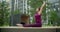 Woman does bends forward to her feet on the bench in the yard of an apartment building, fitness in the urban environment