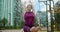 Woman does bends forward to her feet on the bench in the yard of an apartment building, fitness in the urban environment