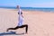 Woman does High Lunch Pose on sea sand beach yoga training sport exercise.