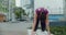Woman does stretching and yoga exercices on the bench in the yard of an apartment building, fitness in the urban