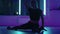 A woman does yoga and stretching on a hanging hammock in neon light. A woman is flying in a hammock in the studio doing
