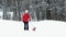 Woman and dog in matching red jackets walking in snow after winter storm.