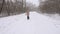 Woman with a dog, runs along the road in the park, in a violent blizzard. Snowing. Slow Motion.