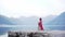 Woman and dog share a moment by a serene lake, mountains in the backdrop.