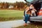 Woman with dog sits in car trunk on autumn road