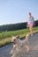 Woman with a dog walking down a gravel street