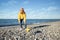 woman with a dog walks on the beach, healthy active small dog runs along the seashore, pet training