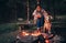 Woman and dog warm near campfire in forest