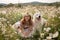 Woman dogs meadow chamomile. Woman embraces her furry friends in a serene chamomile field, surrounded by lush greenery