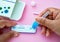 A woman doing Covid-19 Self test. Hand holding coronavirus antigen selftest kit on pink background. Antigen rapid test kit of Cov