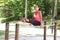 Woman doing dips exercise on balancing bar in park