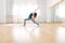 Woman doing high lunge yoga asana in light spacious studio