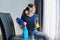 Woman doing house cleaning, female in headphones and gloves with detergent