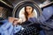 Woman Doing Laundry Reaching Inside Washing Machine