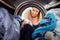 Woman Doing Laundry Reaching Inside Washing Machine