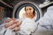 Woman Doing Laundry Reaching Inside Washing Machine