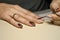 Woman doing manicure for herself with cuticle stainless stick.