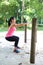 Woman doing squat exercise by the exercise bar in the park