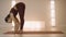 Woman doing standing forward bend pose on mat. Girl stretching in yoga studio