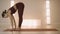 Woman doing standing forward bend pose on mat. Girl stretching in yoga studio