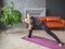 Woman doing yoga asanas at home interior. Girl stretching on exercise mat. Concept of online training and healthy