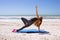 Woman doing yoga on beach in side plank