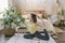 Woman doing yoga exercise in her light stylish bedroom at home. Morning workout in bedroom. Healthy and sport lifestyle.