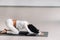 A woman doing yoga on a mat, kneeling makes a bow stretching her arms forward in the gym