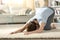 Woman doing yoga melting heart pose on a carpet at home