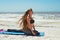 Woman doing yoga pigeon pose on beach