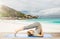 Woman doing yoga in plow pose on beach