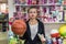 Woman with dollar banknotes and orange ball in toy shop
