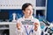 Woman with down syndrome working at scientist laboratory holding your donation matters banner smiling looking to the side and