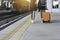 Woman dragging orange suitcase luggage bag, walking in train station. Travel concept