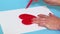 Woman drawing red heart shape close up
